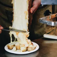 Un morceau de fromage à raclette classique fond sur des pommes de terre. Le fromage dégouline, prêt à être servi.