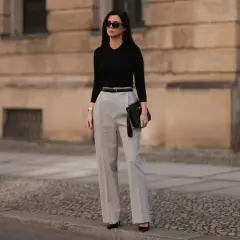 Elegancka stylizacja na imprezę dla 40-latki: czarny top, szare spodnie z wysokim stanem, czarna torebka i okulary.