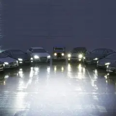 Rząd samochodów z włączonymi światłami, porównanie xenon vs led.