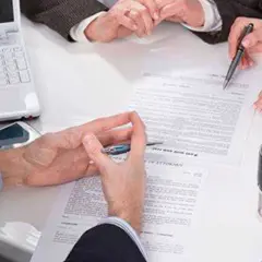 Manos revisando documentos, uno de ellos es un **hipotecante no deudor**, junto a un sello y portátil.