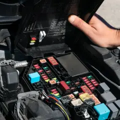 Otwarta skrzynka z bezpiecznikami w komorze silnika Renault Scenic 3. Widać schemat i kolorowe bezpieczniki.