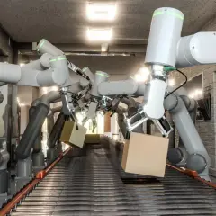 W magazynie coboty co to? Ramię robota chwyta paczkę na taśmie produkcyjnej.