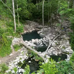 Baignades naturelles dans la forêt, près de Merens-les-Vals. Un sac à dos est posé sur un tronc d'arbre.