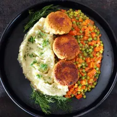 Kotleciki z puree ziemniaczanym i kolorową marchewką z groszkiem, udekorowane koperkiem. Pyszny, domowy obiad.