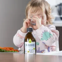 Dziecko pije wodę, obok butelka oleju i talerz z warzywami. To idealny zestaw do nauki samodzielnego jedzenia metodą BLW.