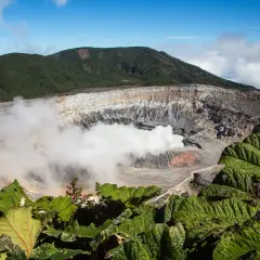 Vulkanen Poás i Costa Rica med sin turkosa sjö och ångande krater, omgiven av frodig grönska.