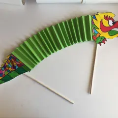 Dragón de papel verde, parte de un manualidades proyecto china infantil. Cabeza colorida y cuerpo en acordeón.