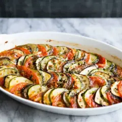 En ugnsbakad ratatouille med skivade tomater, zucchini och aubergine, ett perfekt exempel på enkla vegetariska recept.