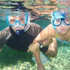 Padre e hija disfrutan del snorkel en la playa de los Muertos, explorando el fondo marino.