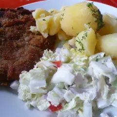 Kotlet schabowy z ziemniakami i surówką z białej kapusty.