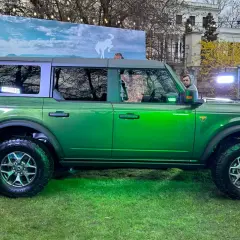Zielony Ford Bronco prezentuje się imponująco na tle krajobrazu z dzikim koniem.