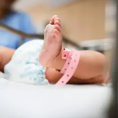 Ett litet barns fot med ett rosa armband, kanske en nyfödd bebis. Vad betyder bb? En ny början.