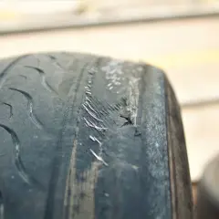 Neumático desgastado con daños visibles, causa de vibraciones por ruedas deformadas.