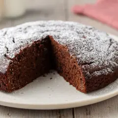 Una fetta è stata tolta da questa torta al cioccolato soffice, cosparsa di zucchero a velo.