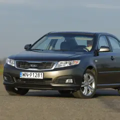 Ciemnoszary Kia Magentis z polskimi tablicami rejestracyjnymi WN 91281 jedzie po asfaltowej drodze.