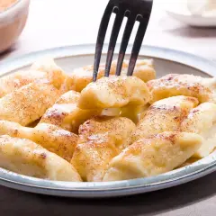 Pyszne pierogi leniwe posypane cynamonem, gotowe do jedzenia. Idealne na szybkie śniadanie lub deser.