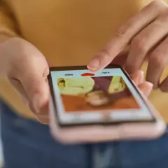 Palec wskazujący dotyka serca na ekranie telefonu, przeglądając profile w poszukiwaniu randek tinder.