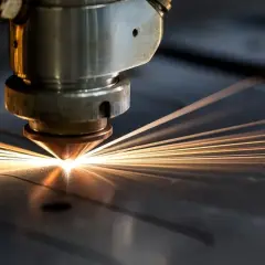 Macchina laser che taglia l'acciaio con un fascio luminoso e scintille.