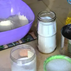 Filiżanki z mąką, cukrem i olejem na kuchennym blacie.