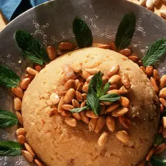 Ein köstlicher Irmik Helvası, garniert mit Mandeln und Minze, auf einem verzierten Silbertablett.