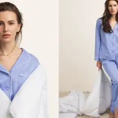 Kobieta w niebieskiej piżamie bawełnianej, owinięta kołdrą, trzyma kubek.