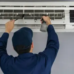 Técnico limpiando un aire acondicionado, paso clave para saber como se instala un aire acondicionado correctamente y mantenerlo.