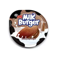Czekoladowe ciastko Milk Burger z kremem, oblane mlekiem, obok szklanki mleka czekoladowego.
