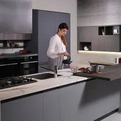 Donna prepara il tè in una moderna isola cucina fai da te con piano in marmo e bancone snack.