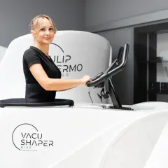Kobieta ćwiczy na rowerze Vacu Shaper, by osiągnąć wymarzone efekty.