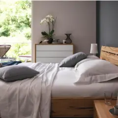 Gemütliches Schlafzimmer mit anthrazit Wand, Holzbett und Blick ins Grüne.