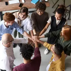 A diverse team joins hands, symbolizing unity and why respect is important for collaboration and shared success.