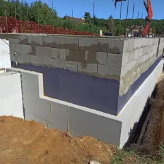 Fundament budynku z bloków betonowych zabezpieczony hydroizolacją. Widoczna izolacja termiczna i przeciwwilgociowa.