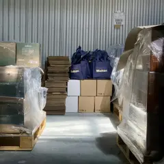 Magazyn gotowy do wysyłki mebli. Palety z paczkami i torby z logo "Merci Walter." czekają na transport.