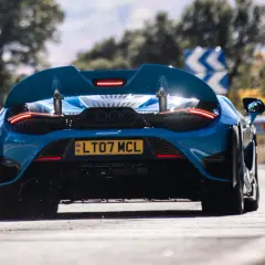 Niebieski McLaren 765LT z czterema końcówkami wydechu pędzi po zakręcie.