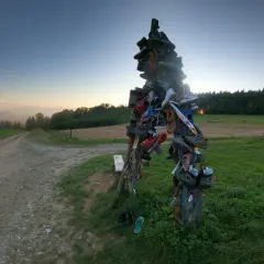 Skopiec szczyt. Rzeźba z butów na szczycie wzgórza, obok polnej drogi, o zachodzie słońca.