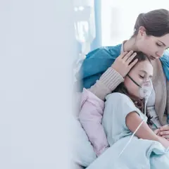 Kobieta pociesza dziecko w masce tlenowej w szpitalu.