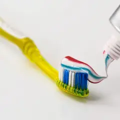 Żółta szczoteczka do zębów z kolorową pastą wyciskaną z tubki.