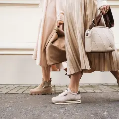 Dwie kobiety w beżowych sukienkach i butach. Jedna ma botki, druga sneakersy. Idealne połączenie: jakie buty do rajstop?