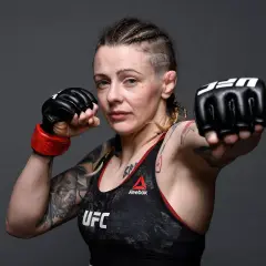 Joanne Calderwood, en MMA-fighter med flätor och tatueringar, visar upp sina boxningshandskar redo för strid.