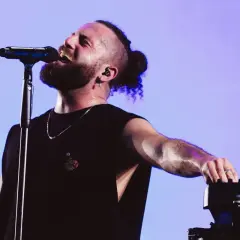 Wokalista Elderbrook na koncercie, zarośnięty, z kucykiem, śpiewa do mikrofonu, dotykając klawiatury.