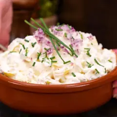 En skål med krämig potatissallad, toppad med rödlök och gräslök. Ett ljuvlig potatissallad recept som passar till allt!
