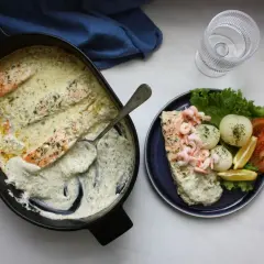 Laxpasta i ugn med krämig sås, serverad med räkor, potatis, tomat och citron. En härlig middag!