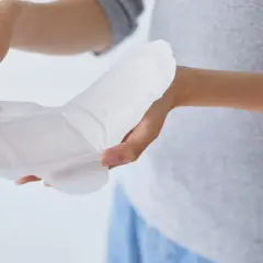 Hände halten ein Inkontinenzprodukt. Fragen Sie Ihren Arzt, wo Sie Inkontinenzmaterial auf Rezept bekommen.