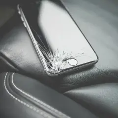 Uszkodzony ekran telefonu leży na skórzanym siedzeniu. Dowiedz się, jak wyświetlić uszkodzony ekran telefonu na komputerze, aby odzyskać dane.