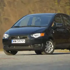 Czarny Mitsubishi Colt na drodze, gotowy do podróży.