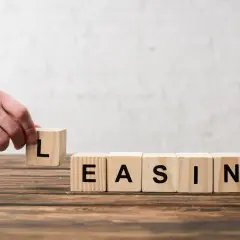 Dłoń układa kostkę z literą "L", tworząc słowo "LEASING". Zastanawiasz się, czy leasing się opłaca?