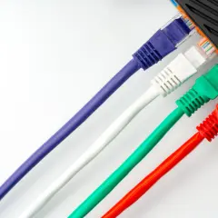 Cables de red de colores (morado, blanco, verde, rojo) conectados a un dispositivo.