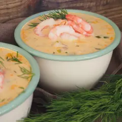 Två skålar med krämig fisksoppa med potatis, toppad med räkor och dill. En härlig svensk rätt.