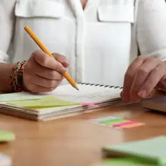 Person plant den **Aufbau einer Unterrichtsstunde** mit Notizen, Büchern und einem Laptop.
