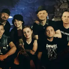 Grupa przyjaciół, zespół Leniwiec, pozuje do zdjęcia w mrocznym wnętrzu.